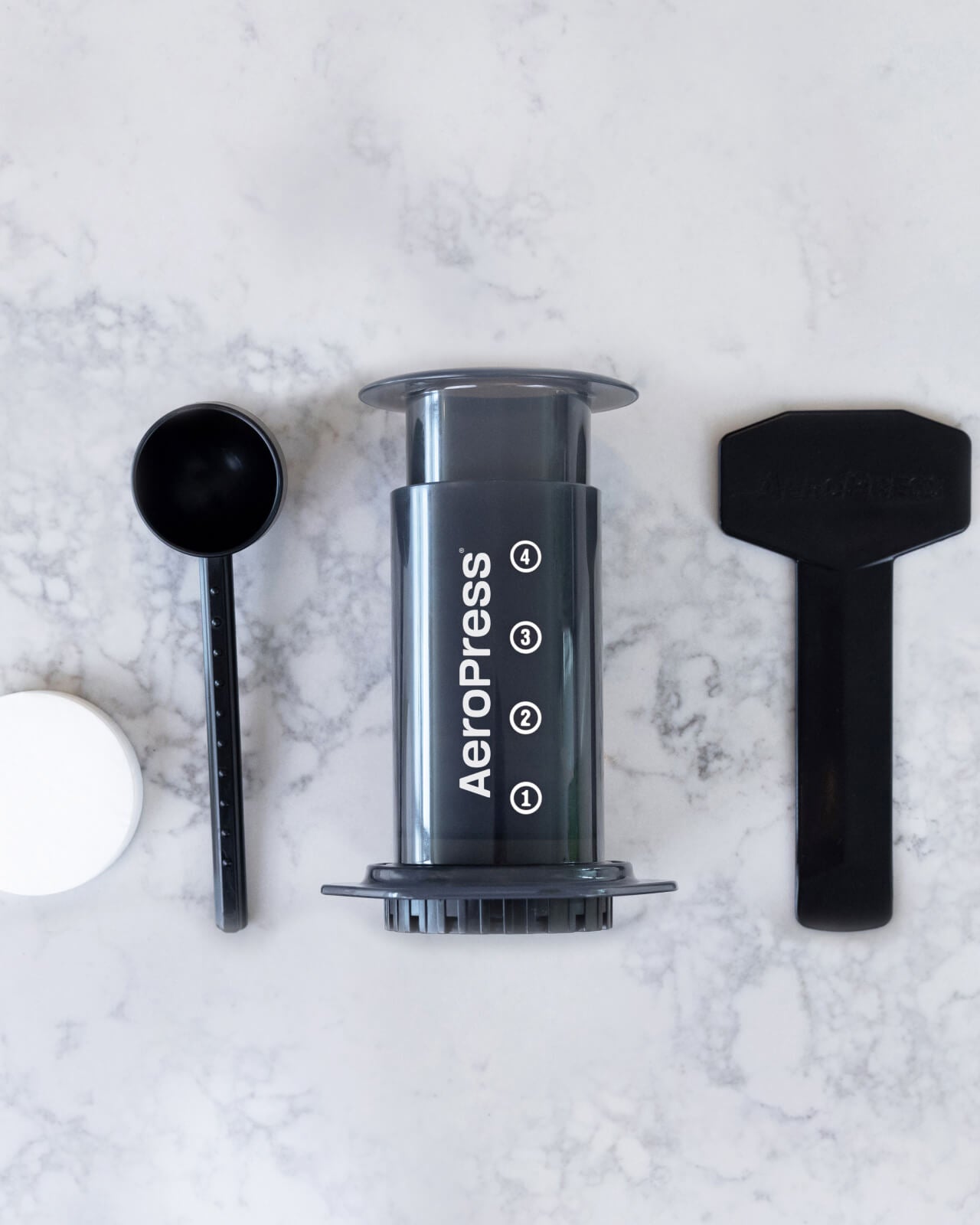 All of what is included with the AeroPress Original Coffee Maker, including a measuring cup, stirring spoon, and AeroPress filters | Equator Coffees