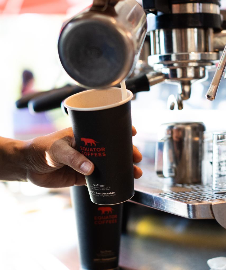 Person pouring coffee into a black Equator Coffees cup | Equator Coffees